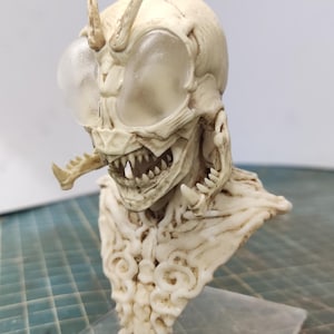 Puede incluir: Un busto blanco, detallado y esculpido de una criatura con grandes ojos translúcidos, dientes afilados y un cuello texturizado de aspecto orgánico.