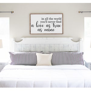 May include: A white bedroom with a white bed, black and white striped pillows, and a wooden sign above the headboard that reads "in all the world you'll never find a love as true as mine".