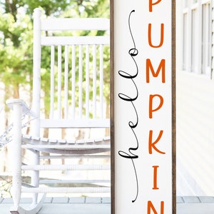 Puede incluir: Un letrero de madera blanco con marco marrón. El letrero dice "hello pumpkin" en escritura negra con la palabra "pumpkin" en letras naranjas.
