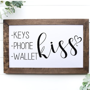 May include: A framed wooden sign with the text "Keys, Phone, Wallet, kiss" in black lettering. The word "kiss" is in cursive with a small heart at the end.