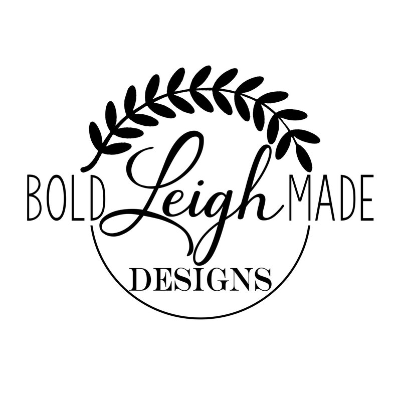 May include: Black and white logo with a wreath of leaves around the text "BOLD Leigh MADE DESIGNS".