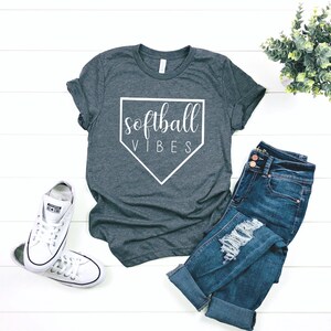 May include: A dark gray t-shirt with a white baseball diamond graphic and the text "softball vibes" in white.
