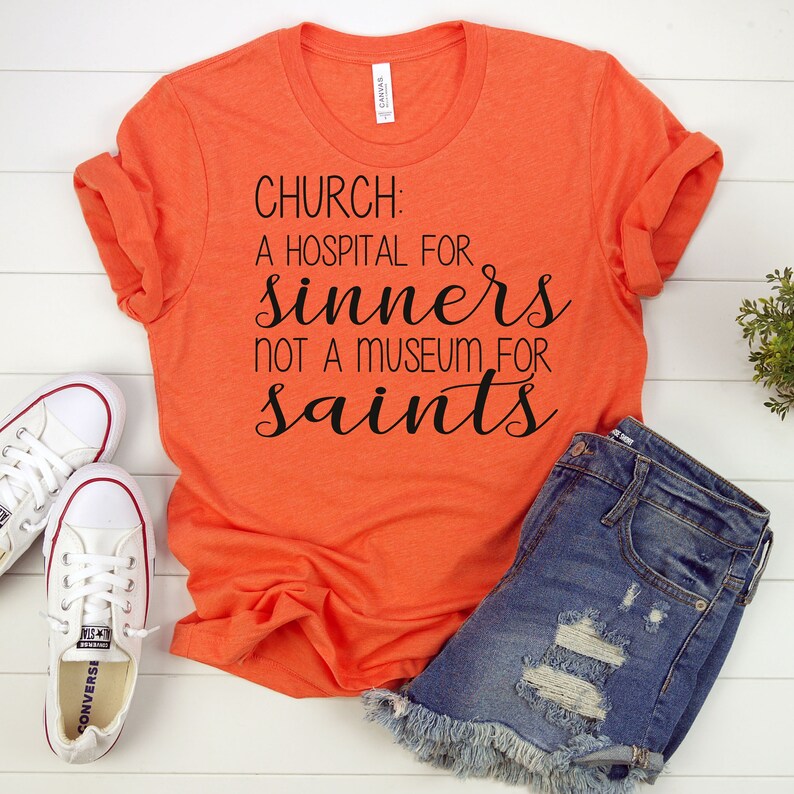 May include: Orange t-shirt with black text that reads "CHURCH: A HOSPITAL FOR SINNERS NOT A MUSEUM FOR SAINTS".