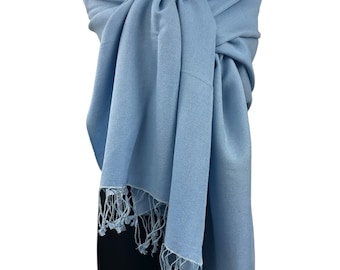 May include: A light blue pashmina shawl with fringed edges. The shawl is draped over a mannequin wearing a black dress and a pearl necklace.