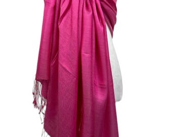 Pode incluir: Um cachecol de seda rosa brilhante com franjas nas bordas. O cachecol está drapeado sobre um manequim branco.