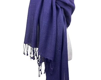 May include: A deep purple rectangular scarf with a woven texture and fringed edges, draped over a mannequin neck form. The scarf features a consistent solid dark violet hue throughout the fabric and is accented by a multi-strand white pearl necklace.