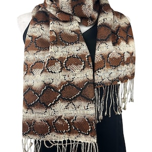 May include: A brown and beige scarf with a snakeskin pattern. The scarf is draped over a black top and has fringe at the ends. The pattern includes diamond and oval shapes.