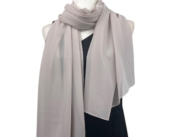 May include: A pale taupe scarf draped over a black dress form. The scarf is made of a sheer, lightweight fabric, with soft folds and a rectangular shape. The scarf is a neutral colour, suitable for various outfits.