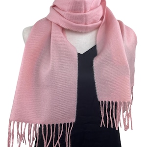 Peut inclure: Une écharpe rose pâle douce avec des franges aux extrémités. L'écharpe est faite d'un matériau léger et est parfaite pour superposer en automne ou en hiver.