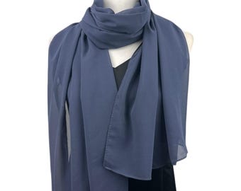 May include: A solid slate blue rectangular scarf made of a lightweight, semi-sheer fabric. The scarf is draped around a mannequin neck, featuring soft folds and a smooth, finished hem along the edges, creating a simple and clean appearance.