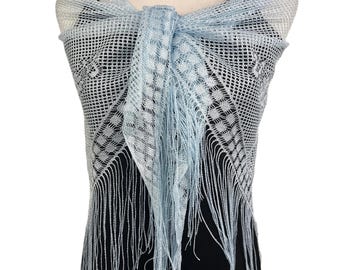 Peut inclure: Un châle en dentelle bleu clair avec un motif délicat et une bordure à franges. Le châle est drapé sur un mannequin portant une robe noire et un collier de perles.