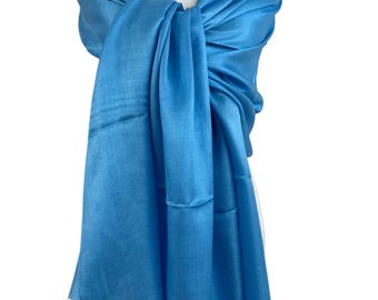 May include: A light blue silk shawl with fringe. The shawl is draped over a white mannequin with a pearl necklace.