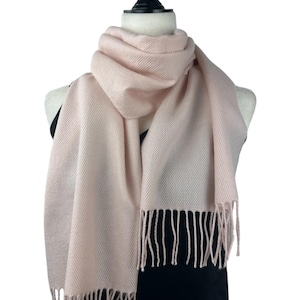Peut inclure: Une écharpe rose pâle avec des franges aux extrémités. L'écharpe est drapé autour du cou d'un mannequin.