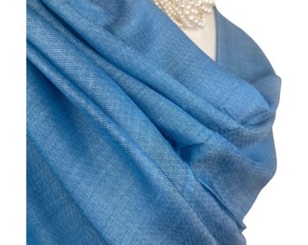 May include: A light blue sheer scarf with a subtle woven pattern. The scarf is draped over a mannequin's shoulders.