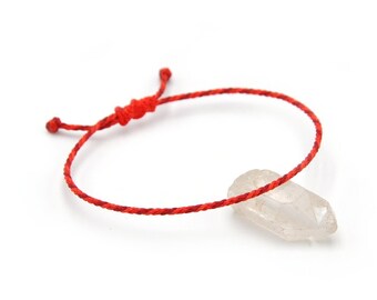 Könnte beinhalten: Ein rotes Armband mit einem Anhänger aus klarem Quarzkristall.