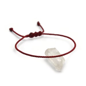 以下が含まれることがあります： 赤い紐のブレスレットに、透明な水晶のペンダントがついたもの