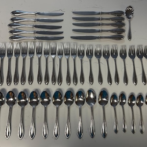 May include: A large collection of stainless steel flatware including ten dinner knives, twenty-two forks of varying sizes, and fifteen spoons of varying sizes, all featuring a smooth, tapered handle design with a simple, polished finish.