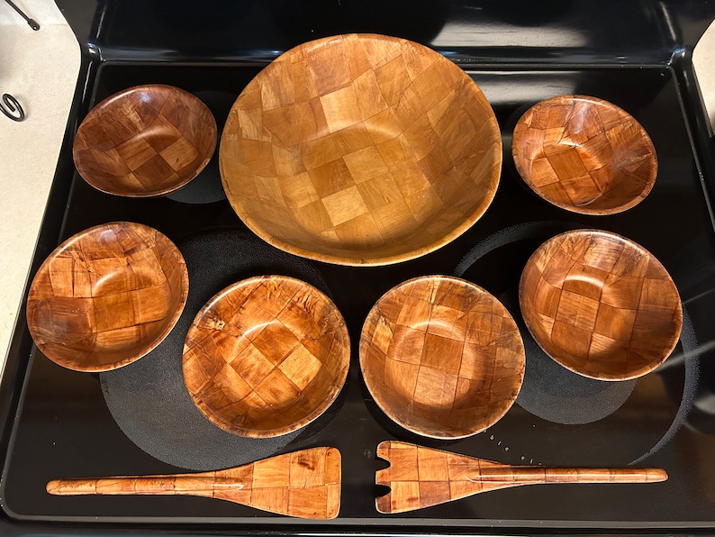 Pu&ograve; includere: Un set di sette insalatiere in legno e un cucchiaio per insalata in legno. Le insalatiere sono tutte in legno intrecciato e hanno un colore marrone naturale. Il cucchiaio &egrave; anch'esso in legno intrecciato e ha un colore marrone naturale.