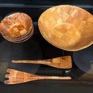 Pu&ograve; includere: Un set di insalatiere e utensili da servizio in legno. Il set comprende una ciotola grande, quattro ciotole pi&ugrave; piccole, un cucchiaio da portata e una forchetta da portata. Tutti i pezzi sono in legno naturale con un motivo intrecciato.