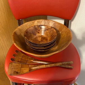 Pu&ograve; includere: Un set di insalatiere e utensili da servizio in legno. Le insalatiere sono annidate l'una dentro l'altra e sono realizzate in legno marrone chiaro con un motivo intrecciato. Gli utensili sono anch'essi in legno e presentano un motivo intrecciato.