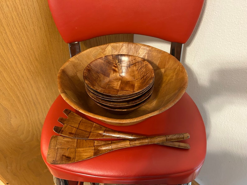 Pu&ograve; includere: Un set di insalatiere e utensili da servizio in legno. Le insalatiere sono annidate l'una dentro l'altra e sono realizzate in legno marrone chiaro con un motivo intrecciato. Gli utensili sono anch'essi in legno e presentano un motivo intrecciato.