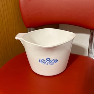 May include: White ceramic pitcher with a blue floral design. The pitcher has a square shape and a spout.