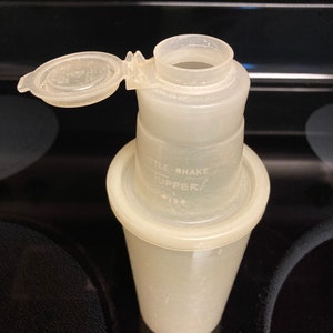 May include: A white plastic shaker bottle with a clear lid. The bottle has the text "Ttle Shake Upper/ 415.8" printed on the side.