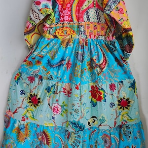 Peut inclure: Une longue robe &agrave; volants avec un corsage en patchwork pr&eacute;sentant une vari&eacute;t&eacute; de motifs floraux et g&eacute;om&eacute;triques color&eacute;s. La jupe est d'un bleu &eacute;clatant avec un imprim&eacute; floral.