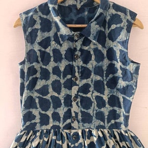 Puede incluir: Un vestido sin mangas azul y blanco con estampado, con cierre de botones en la parte delantera y falda fruncida.