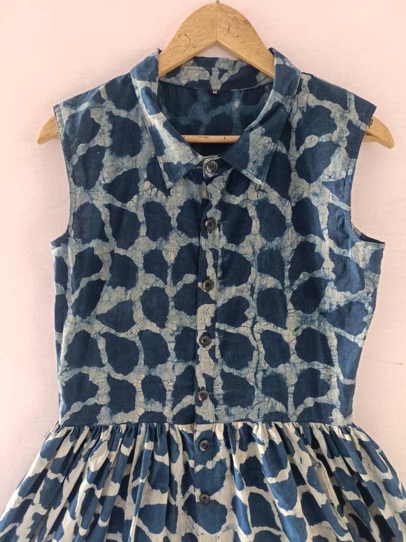Puede incluir: Un vestido sin mangas azul y blanco con estampado, con cierre de botones en la parte delantera y falda fruncida.