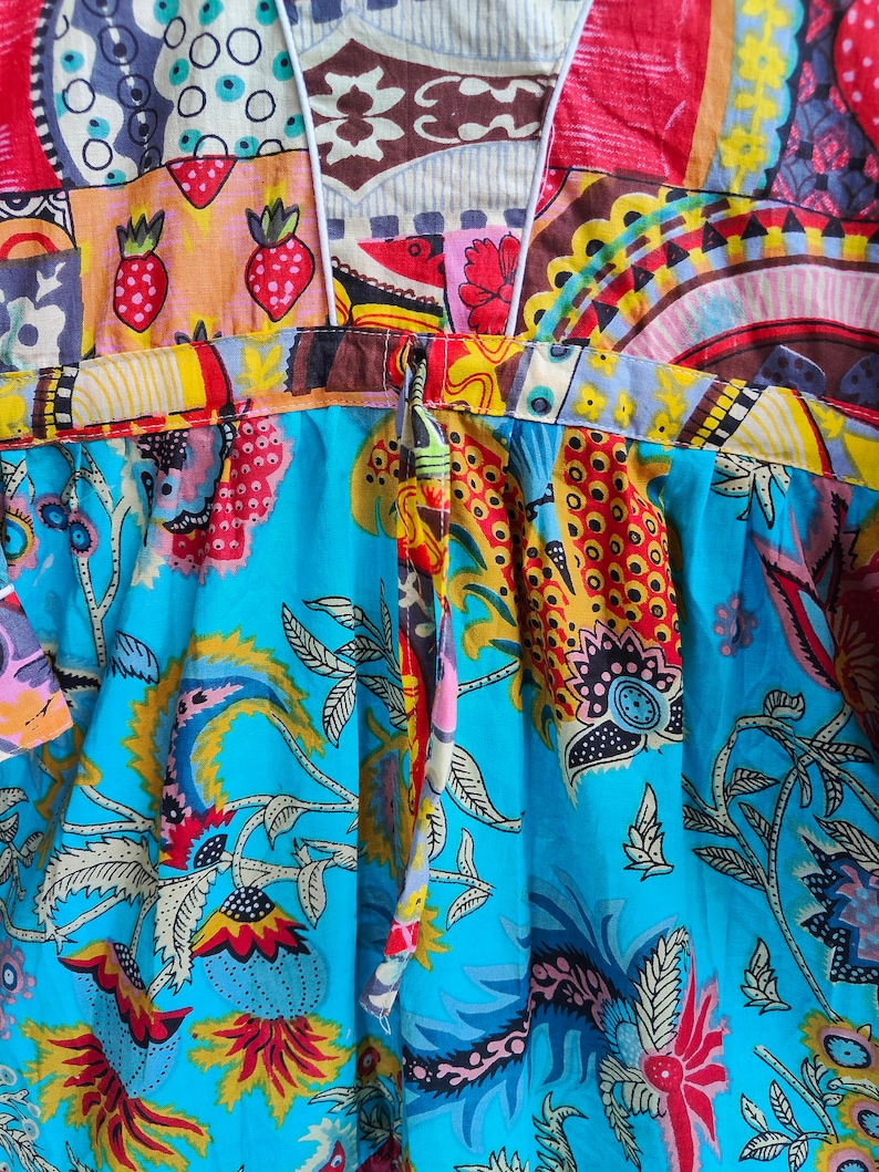 Peut inclure: Une robe &agrave; motifs bleus et blancs avec un motif floral color&eacute;. La robe a un col en V et une fermeture &agrave; nouer dans le dos.