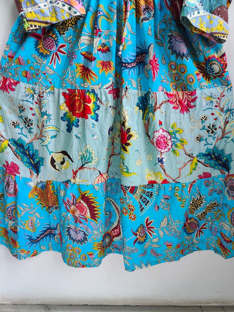 Peut inclure: Une robe &agrave; imprim&eacute; floral bleu et blanc avec une jupe &agrave; volants. La robe est de style patchwork avec diff&eacute;rents motifs floraux.