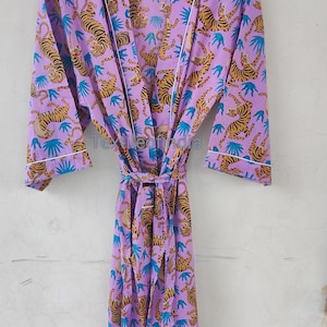 May include: A lilac-colored robe with a repeating pattern of tigers and blue leaf shapes. The robe has a white trim and a matching tie belt. The text "Textileofindia" is visible on the robe.