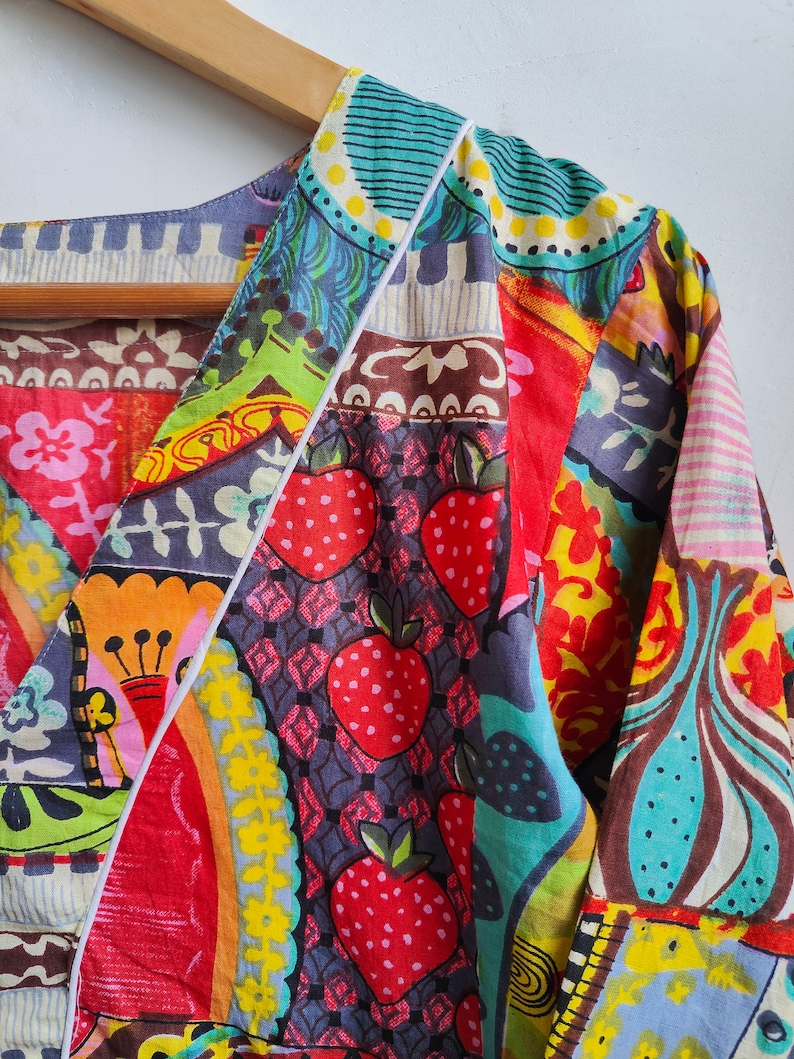 Peut inclure: Une chemise color&eacute;e &agrave; motifs multiples avec un col en V et des manches longues. Le tissu pr&eacute;sente un design patchwork avec diff&eacute;rentes formes g&eacute;om&eacute;triques, des motifs floraux et des fraises.