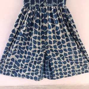 Puede incluir: Un vestido estampado en azul y blanco con cierre de botones en la parte delantera y falda fruncida.