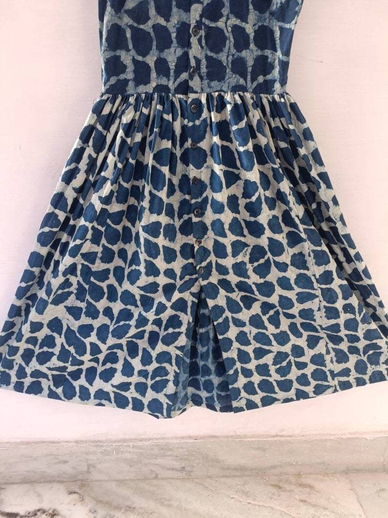 Puede incluir: Un vestido estampado en azul y blanco con cierre de botones en la parte delantera y falda fruncida.