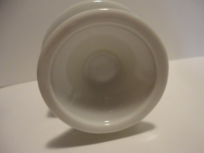 May include: White ceramic pedestal with a round base and a smooth, glossy finish.