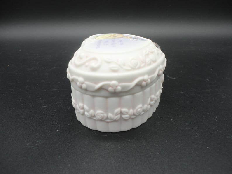 Puede incluir: Un joyero de porcelana blanca en forma de coraz&oacute;n con acabado mate y detalles en relieve de rosas y enredaderas en los laterales. La tapa muestra una ilustraci&oacute;n impresa de un personaje rubio e incluye el texto, Love is the best gift.