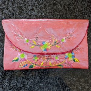 Cartera de seda con bordado intrincado, detalles florales, cuentas y correa negra; varios colores vibrantes; hecha en Vietnam.