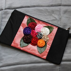 Cartera con flores de seda intrincadas; fondo en tonos rosa claro sedoso o tierra sobre hilos de color negro; elegante cartera; hecha en Vietnam.