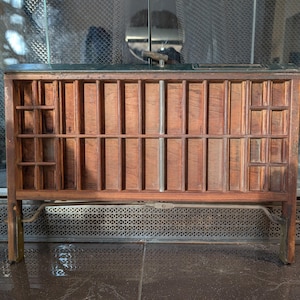 Puede incluir: Una bandeja de imprenta de madera con una cuadrícula de divisores verticales y horizontales. La bandeja está hecha de madera de tonos cálidos y tiene forma rectangular. Tiene una parte superior verde oscuro y está sostenida por cuatro patas.