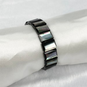 May include: A black bracelet with rectangular iridescent shell beads.