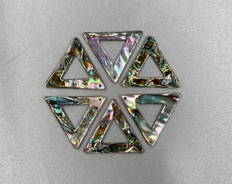 May include: Six iridescent abalone shell triangle pendants. Each triangle has a hole at the top for stringing. The shells display a range of colors, including green, purple, and silver. The pendants are arranged in a hexagonal pattern.