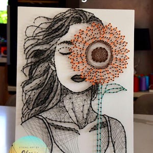 May include: String art portrait of a woman with a sunflower covering one eye. The artwork is made with black thread on a white canvas. The sunflower has orange and brown accents. The words "Digital file" are at the top.
