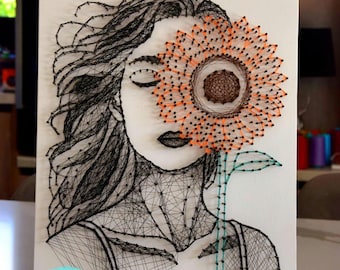 La ragazza con il modello e le istruzioni per realizzare un girasole con la tecnica dello string art, file digitale fai da te con il girasole, artigianato fai da te con il string art e il girasole