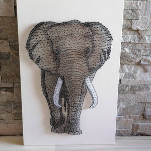 Pode incluir: Uma escultura de arame preto da cabeça e parte superior do corpo de um elefante sobre um fundo de tela branca.