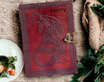 May include: A burgundy leather journal with a dragon design embossed on the cover. The journal has a brass clasp and is personalized with the name "Harry".