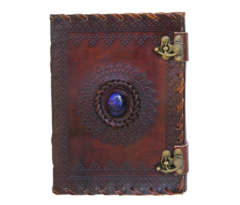 Personalised Handmade refillable Brown tanned Genuine leather bound journal Book of shadow grimoire feature Vintage emboss, secured metal Clasp closure, ideal for writers, poets, artists, painters, rest on vintage table with pen besides.