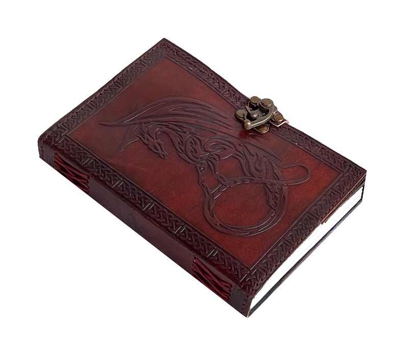 Handmade Refillable tan Brown Premium leather bound journal Magic mystical feature dragon embossed, secured with brass polish metal clasp closure, ideal spell book, travel diary, rustic guest book, rest on vintage table with pen.