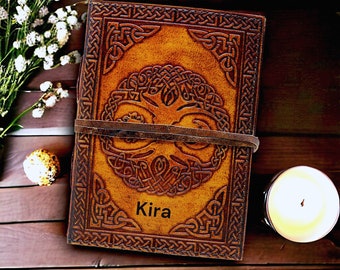 Può includere: Un diario in pelle fatto a mano con un design celtico dell'albero della vita e il nome "Kira" impresso sulla copertina. Il diario è assicurato con un cinturino in pelle e presenta un'intricata lavorazione a nodi. La copertina è di colore marrone caldo.